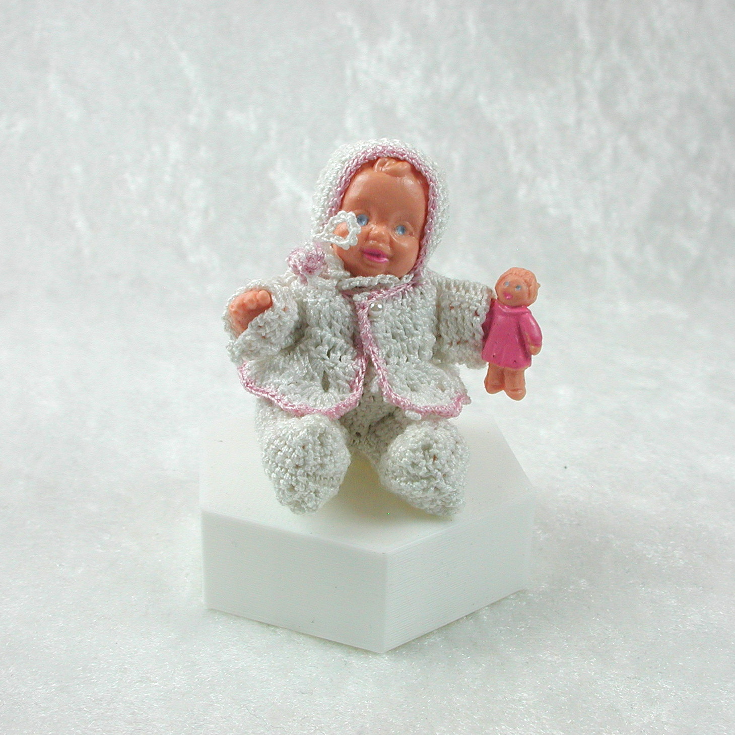 Sitzende Puppe in gehäkelter Kleidung in Miniatur