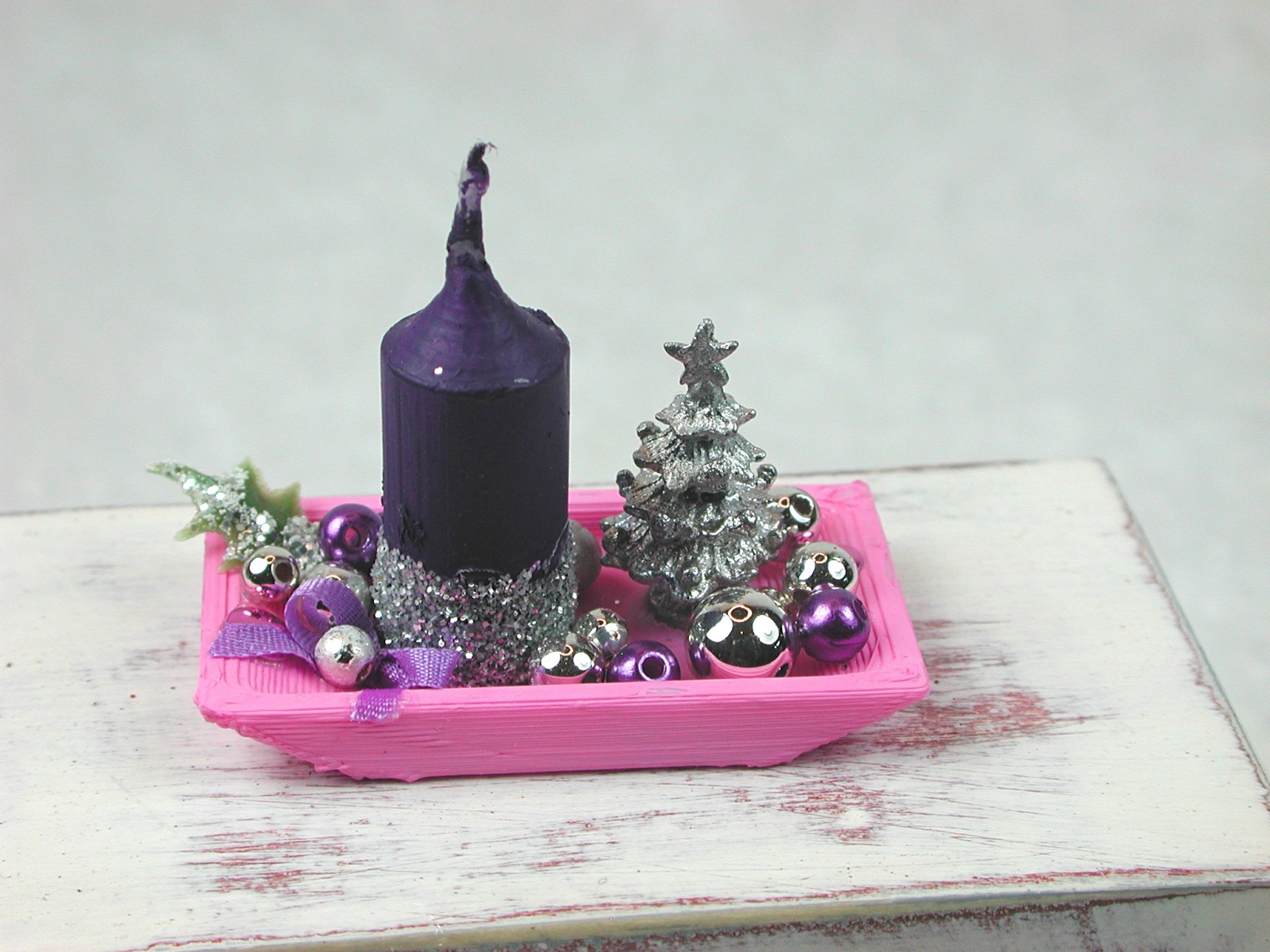 Rechteckige rosa Kunststoffplatte mit hochgebogenen Seiten mit violetter Kerze in weihnachtlicher